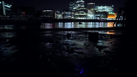 london skyline at night, the shard, buildings and skyscrapers, view from the river thames at low tide, beautiful light reflections in the water