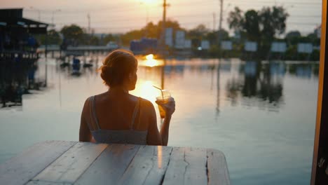 hermosa joven disfrutando de una bebida refrescante al atardecer