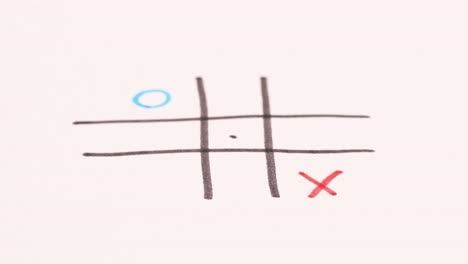 playing noughts and crosses on a piece of paper with red and blue markers