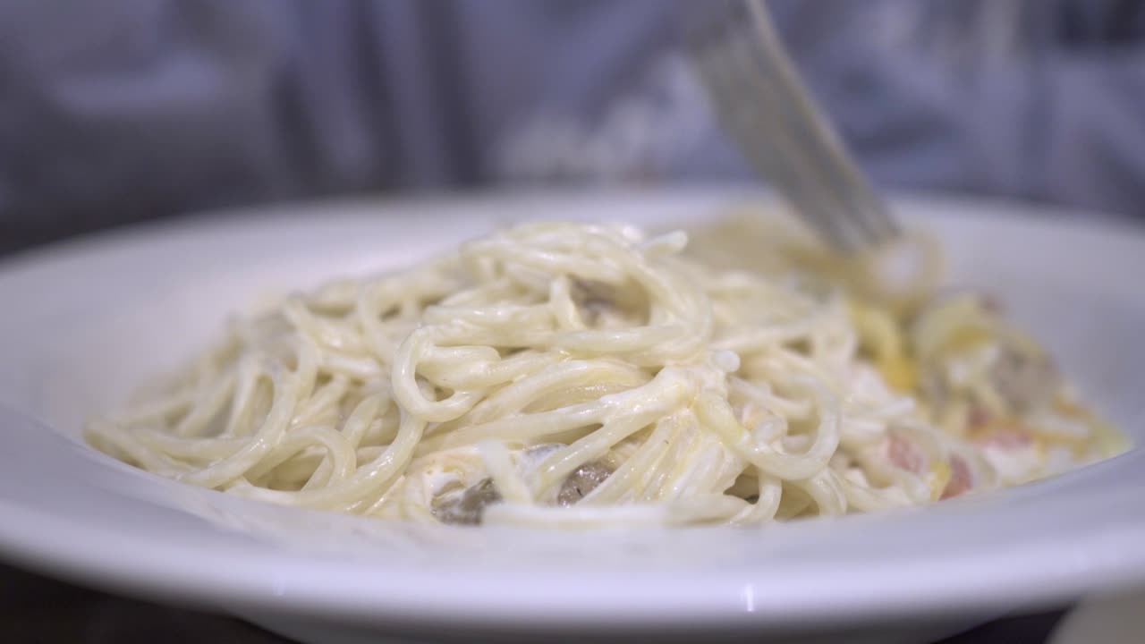 un niño come pasta de crema en un restaurante. la mano del niño está sosteniendo un tenedor.