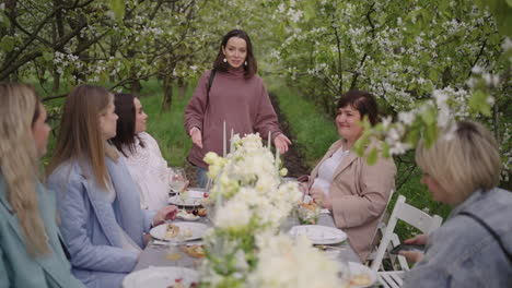 fiesta de gallinas en el jardín en flor en el día de primavera las mujeres están sentadas en la mesa con decoración de flores