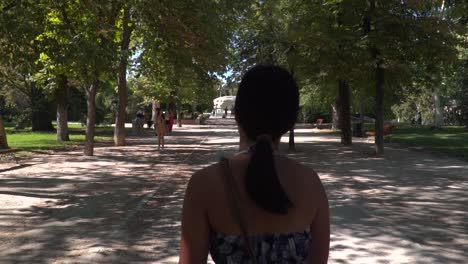 back view of girl with summer dress walking through park madrid