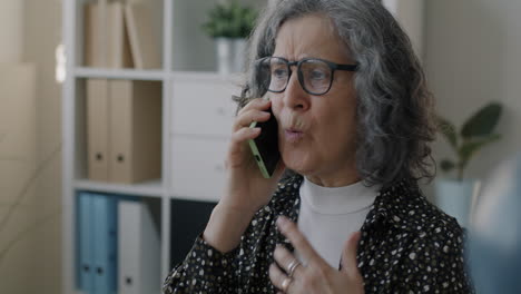 senior woman talking on phone in office