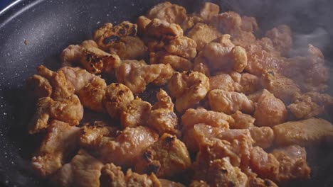 adding cooking oil to pieces of floured chicken in a frying pan, close up view