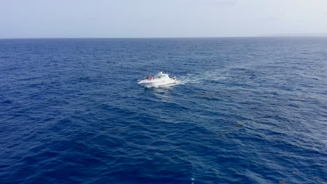 Incredible-aerial-shot-in-the-open-sea-with-a-view-of-a-white-boat-sailing-in-cap-cana,-Dominican-Republic