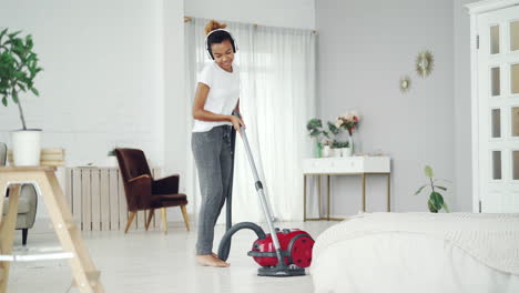 woman cleaning her bedroom with headphones