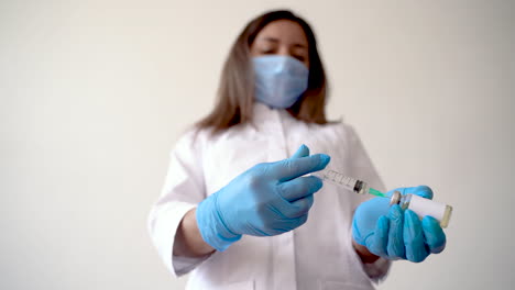 female nurse filling a syringe with a vaccine vial for covid 19 2