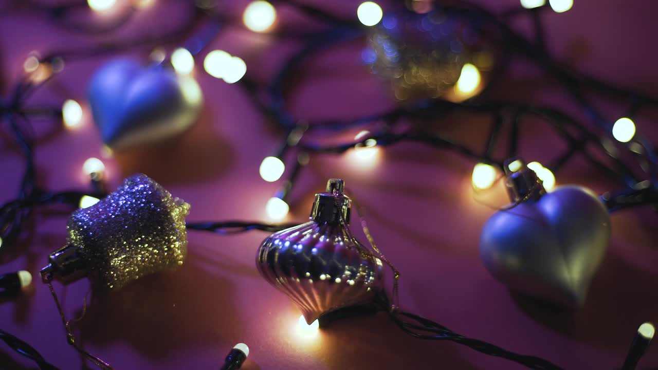 крупный снимок гирлянды с золотыми огнями и рождественскими игрушками на цветном фоне. рождественская концепция. декорация дома. красивый бокех