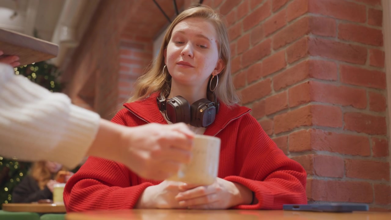 Giovane cameriera che serve una bevanda calda a una cliente in un bar