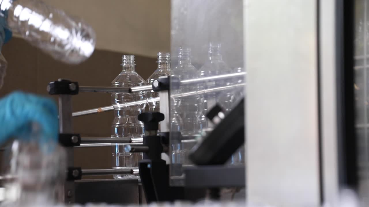 un trabajador coloca botellas de plástico vacías en una línea de cinta transportadora para prepararlas para llenarlas con vinagre en una fábrica