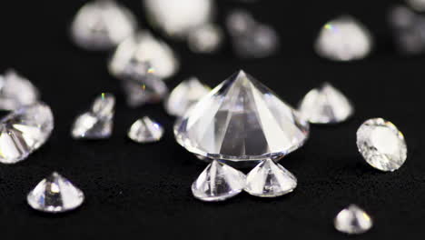 toma macro en cámara lenta de diamantes reales de corte brillante de varios tamaños cayendo por la mesa de clasificación negra en una joyería