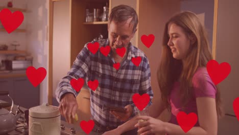 animación de iconos de corazón sobre el padre y la hija caucásicos cocinando