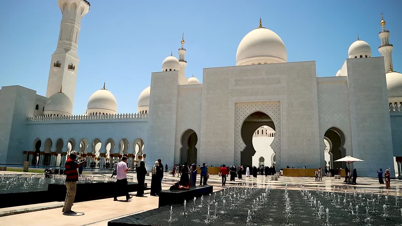 Massive entrance with fountain into Sheikh Zayed Grand Mosque, pan right shot