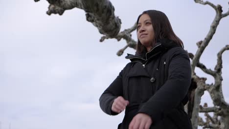 joven mujer atractiva cruza los brazos y disfruta del elegante ambiente silencioso de invierno en un árbol