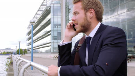 jonge zakenman die aan de telefoon praat terwijl hij loopt