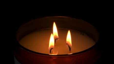 cámara lenta, tres velas ardiendo con fondo oscuro