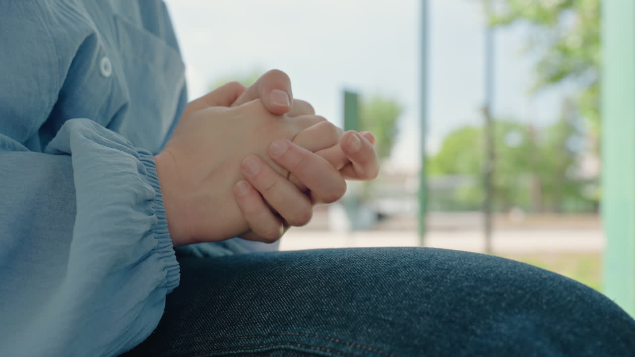 manos apoyadas en la rodilla cubierta por unos vaqueros, cuidador haciendo una pausa durante un descanso al aire libre en un porche iluminado por el sol; el detalle de la manga suave y la palma capturan un momento tranquilo de reflexión y calma, textura del denim y la piel visible