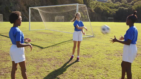 playing soccer on school field, girls passing ball near goalpost