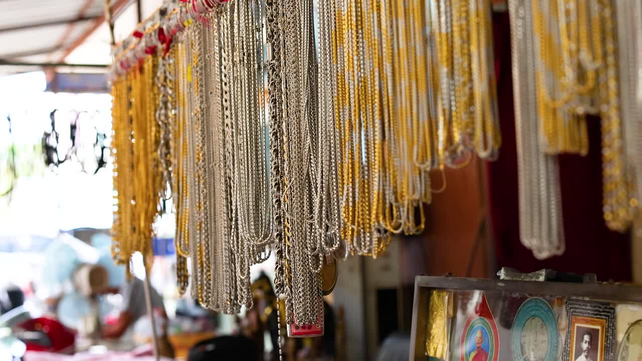 Colorful necklaces hang in a bustling market stall, capturing the lively atmosphere of a Phuket marketplace