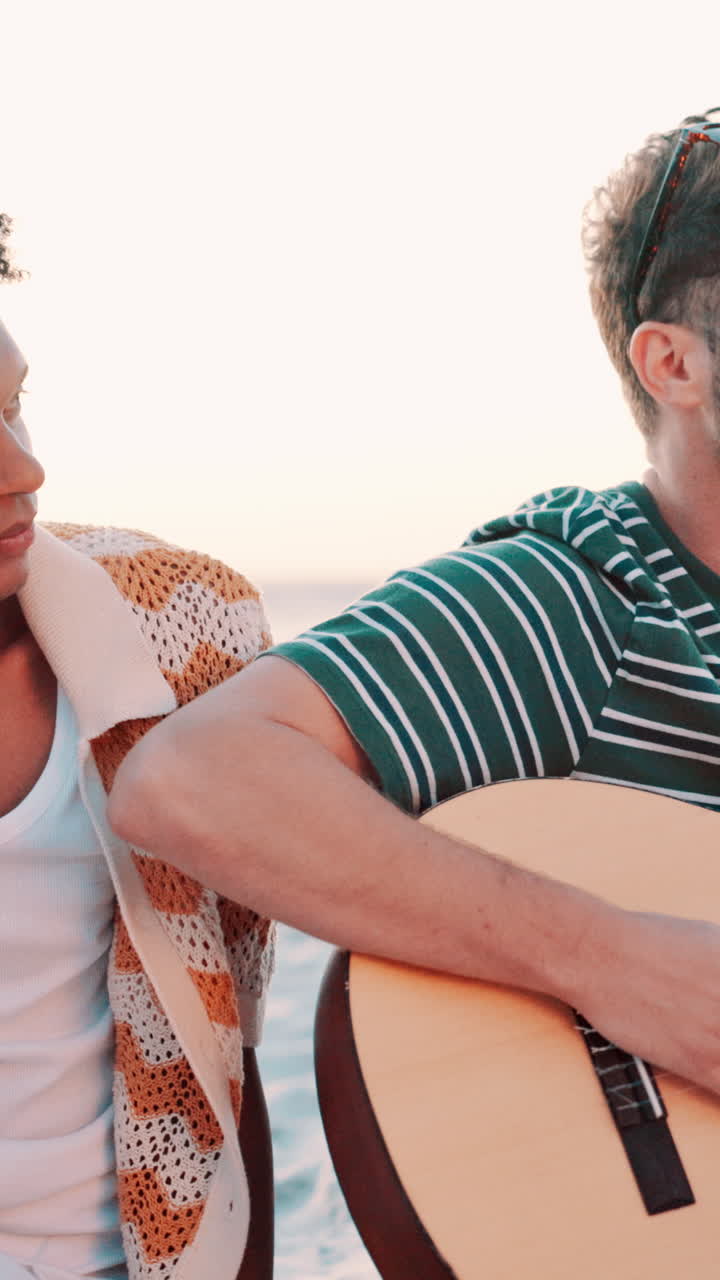 Dos hombres tocando la guitarra y cantando en la playa al atardecer