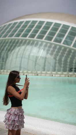 girl taking picture of modern architecture near a pool