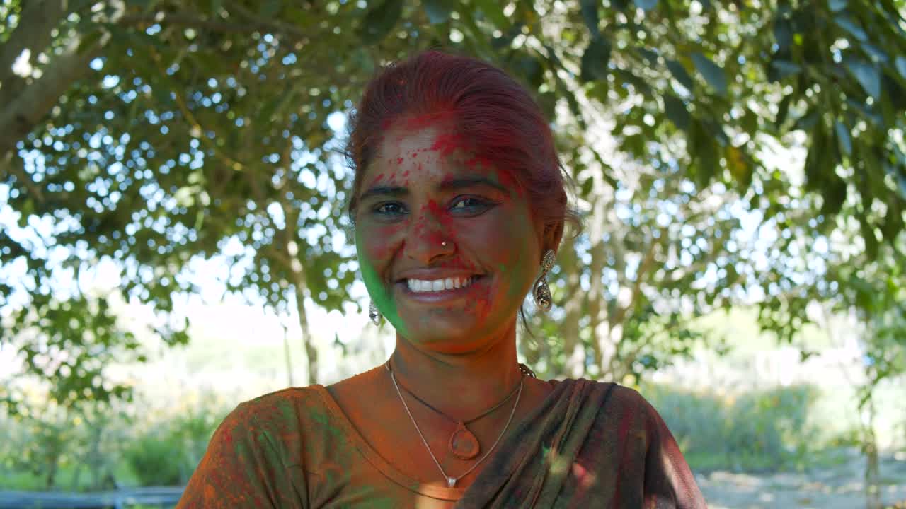 인도 여성의 가까운 얼굴은 밝은 홀리 색으로 얼룩져 있습니다.