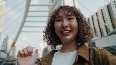 young asian woman taking selfie in city
