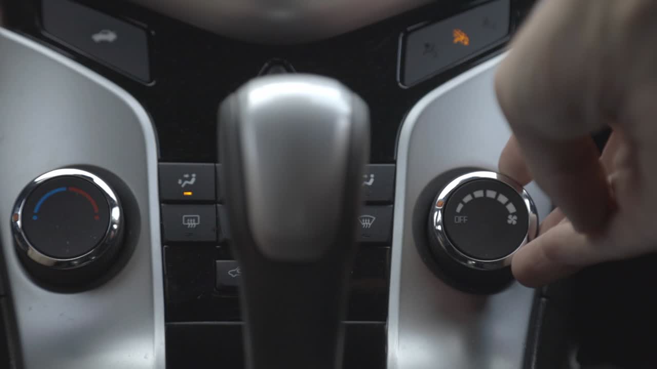 Driver's Hand Turning On The Car Temperature Knob Near The Center Console - close up slowmo