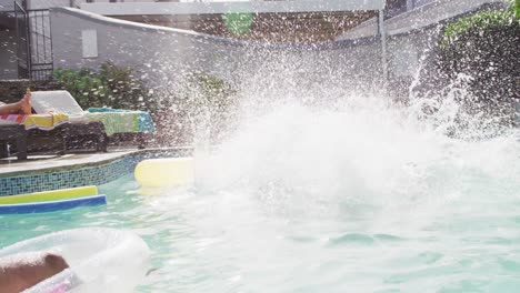 group of happy diverse female and male friends ,jumping into swimming pool at pool party