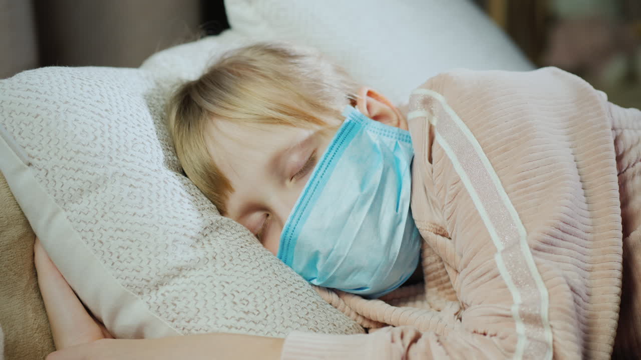 Una donna poggia la mano sulla fronte di un bambino che dorme per controllargli la temperatura.