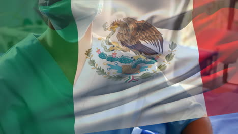 mexico flag waving against female senior health worker wearing face mask at hospital