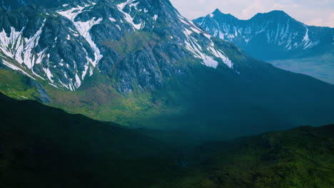 Aerial-Over-Valley-With-Snow-Capped-Mountains-In-Distance