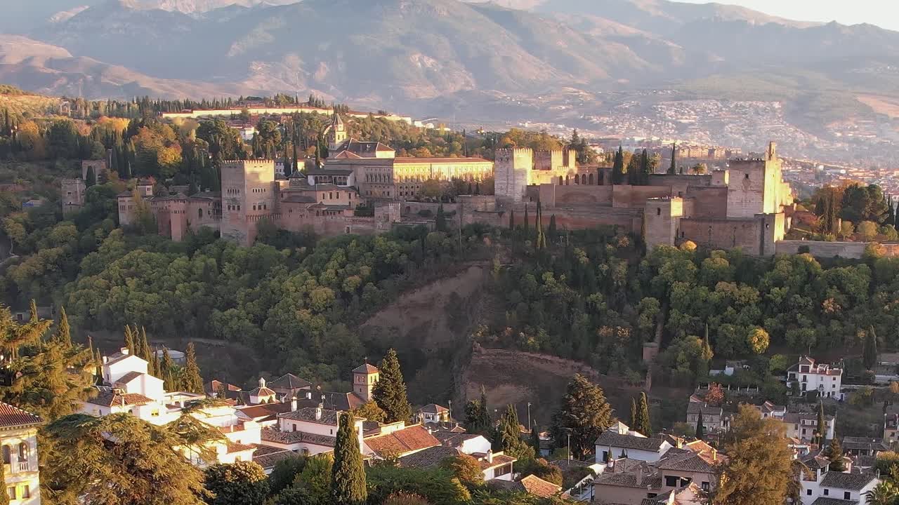 Vista do palácio de Alhambra em Granada com montanhas ao fundo durante o pôr do sol