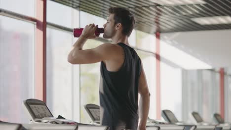 athlete man drinking water at cardio training on treadmill machine.