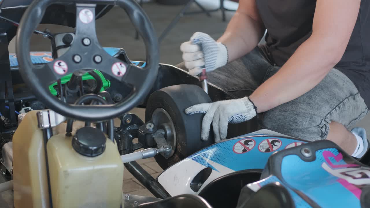 el mecánico del servicio de carreras de go kart cambia las ruedas