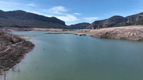 Aerial-flying-above-Sau-reservoir-at-extreme-low-levels,-resurface-church