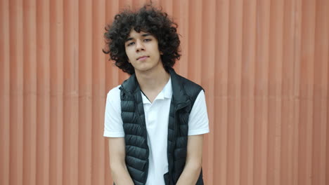 teenager with crossed arms in front of orange wall