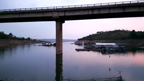 floating village at sunset under a bridge