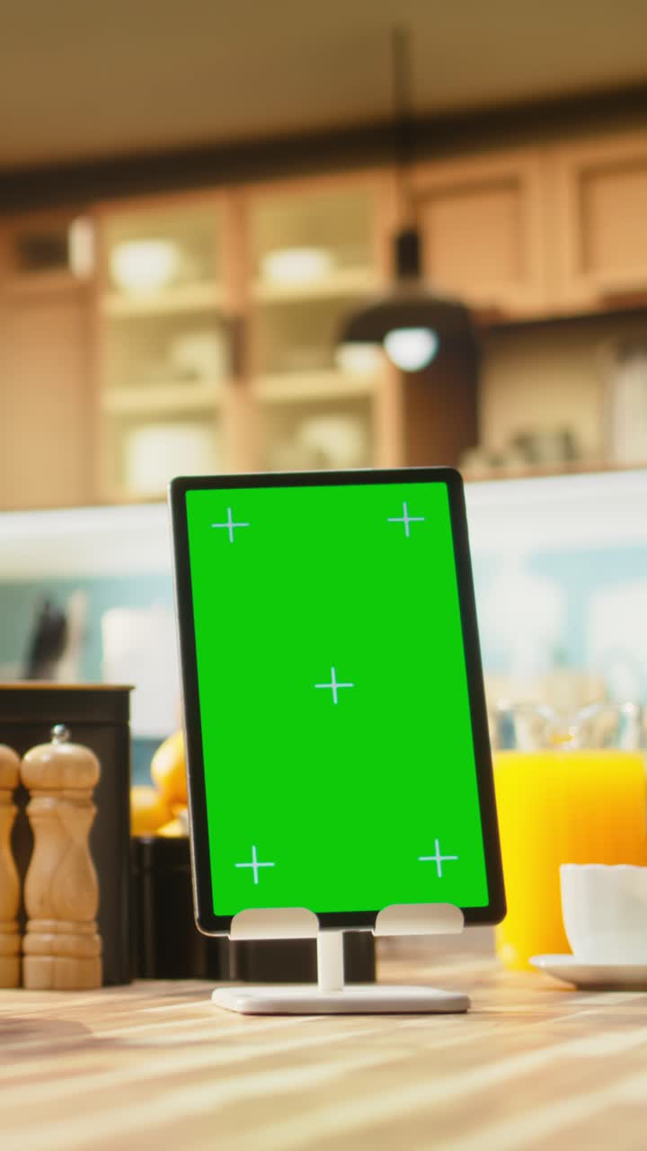Vertikal video: Vertikal grøn skærm på tablet i et tomt, moderne køkkenområde.