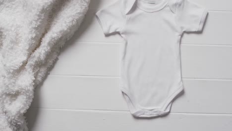 video of white baby grow and white furry rug with copy space on white background