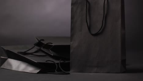 black gift bags with black handles on dark grey background with copy space