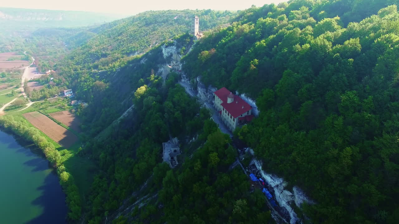Gorgeous rock monastery built on the sloping mount. Amazing mountains with a river at the foot. Top view.
