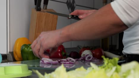 Nahaufnahme-Von-Händen-In-Einer-Küche,-Die-Eine-Zwiebel-In-Zwiebelringe-Schneidet