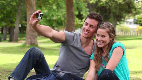 two friends sitting together before using a camera to take a picture of themselves