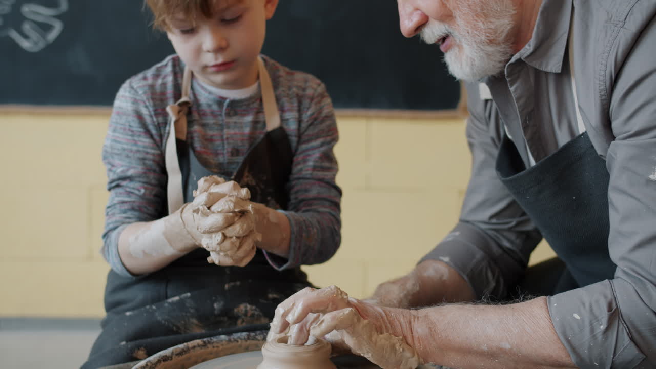 Grandfather teaching a boy pottery