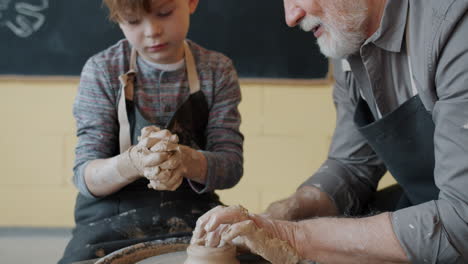 grandfather teaching a boy pottery