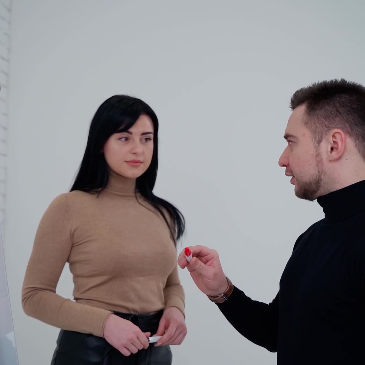 Business couple develops new project. Young man is sharing his ideas written on white board with a beautiful woman in office.