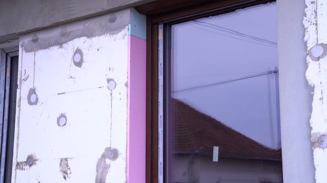 Exterior house wall with sealed window frame and visible foam board insulation