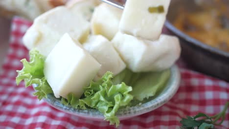 close-up of cubed white cheese on lettuce in a bowl