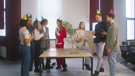 group of multiethnic colleague with party hat spending time together, drinking and toasting at the office party